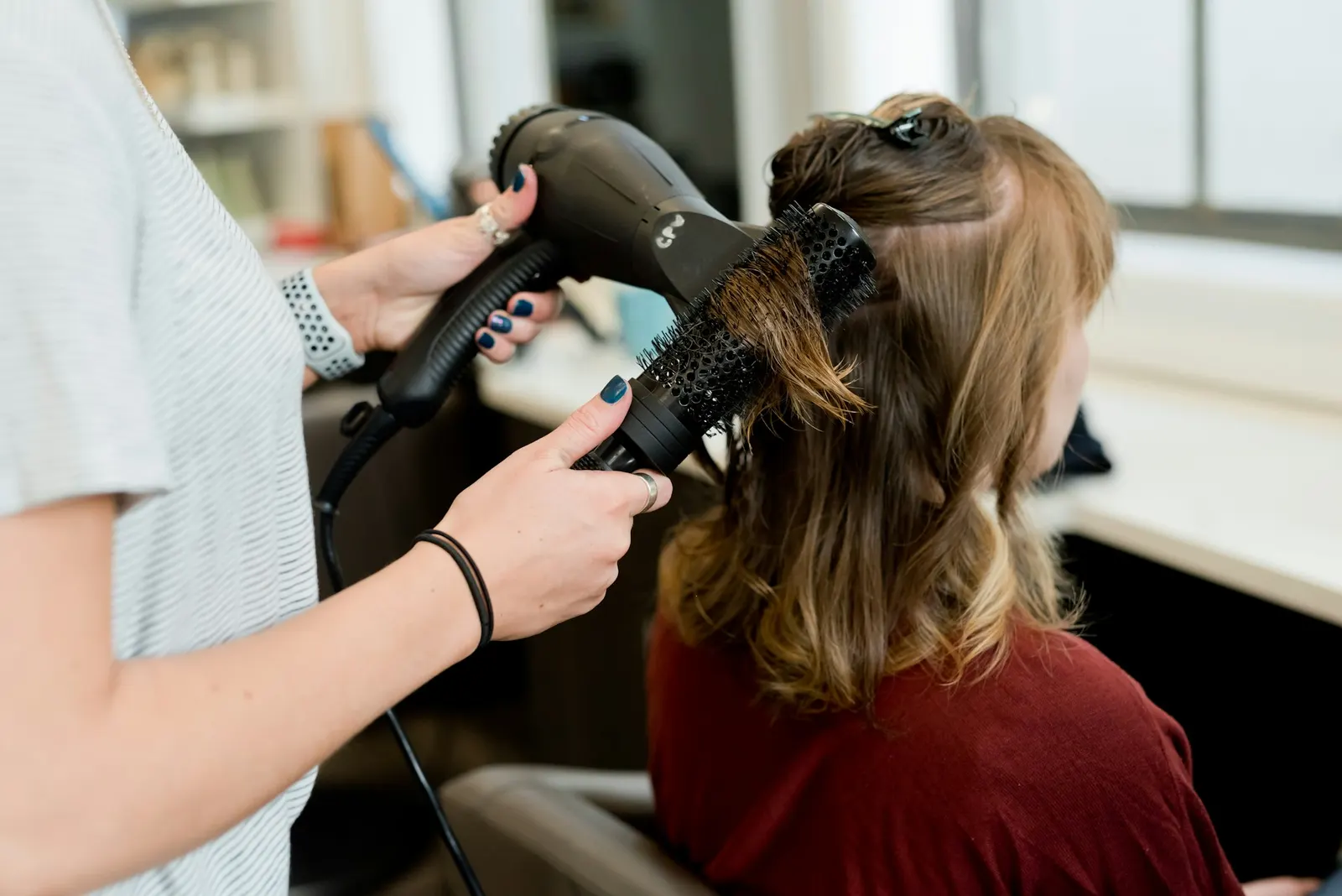 Peluquera secando el pelo de una clienta en el salón